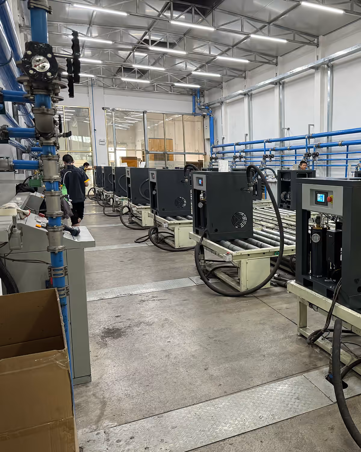 Screw compressors on roller conveyors inside a workshop